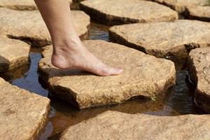 Woman stepping on stone in middle of stream